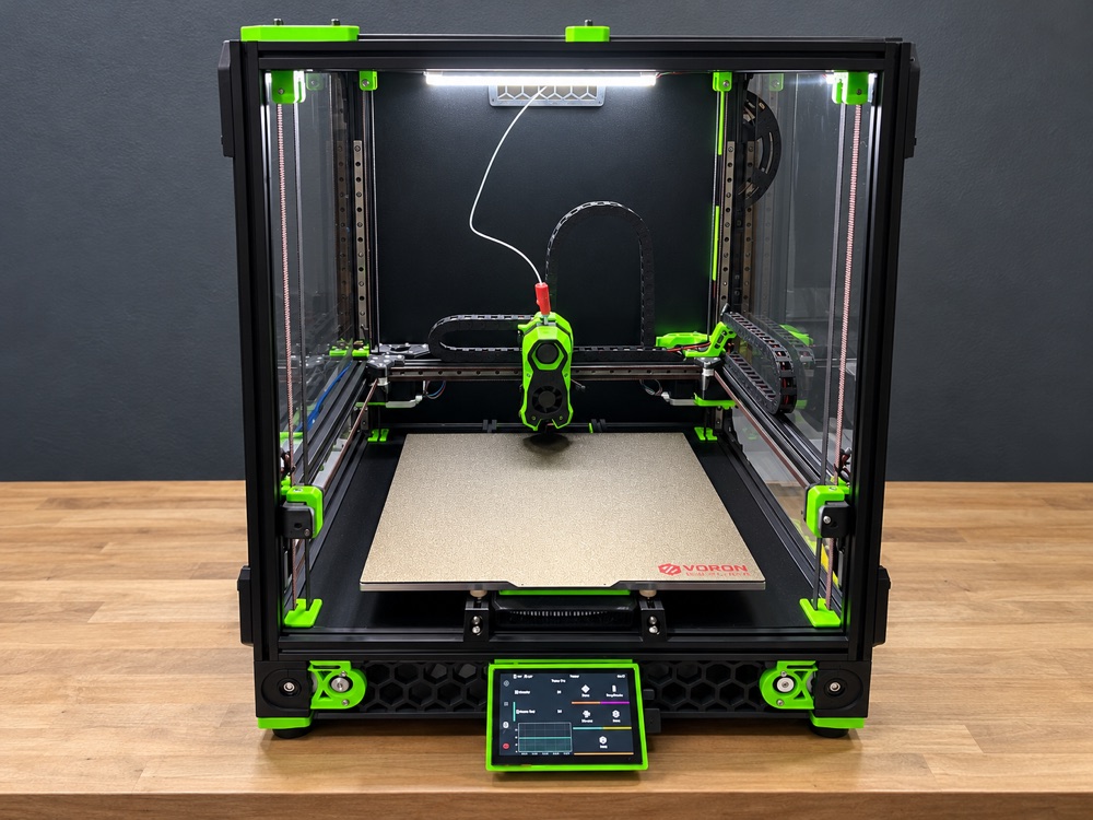 Black-framed 3D printer with bright green printed components, a textured print bed, and a front touchscreen.